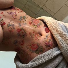 the back of a woman's body covered in flowers and towels with her eyes closed