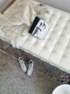 there is a white bench with shoes on it and a book in front of it