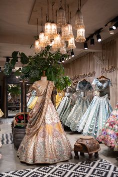 a store with lots of different types of dresses on display in front of lamps and chandeliers