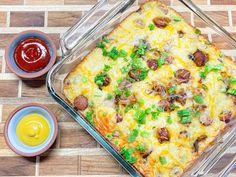 a casserole dish with green onions, sausage and cheese next to condiments