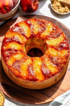 a pineapple upside down cake sitting on top of a wooden cutting board next to bowls of fruit