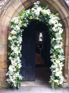 an archway with flowers and greenery on the door way to a church in england