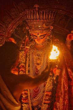 a person lighting a candle in front of a statue