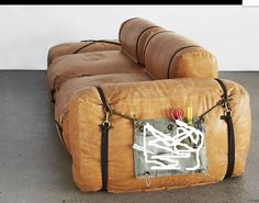 a large brown couch sitting on top of a cement floor next to a white wall