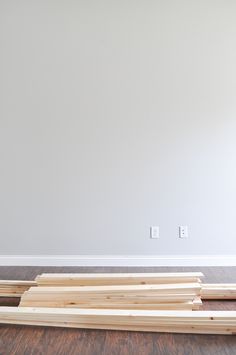 several pieces of wood laying on the floor in front of a wall with two white outlets