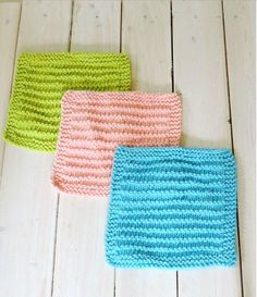 three crocheted dishcloths sitting on top of a white wooden floor next to each other