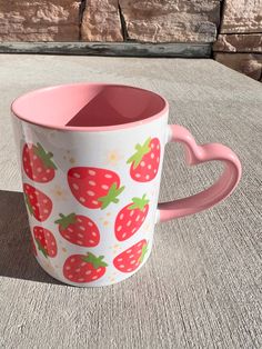 a pink and white coffee cup with strawberries on it