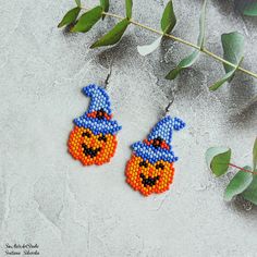 the beaded pumpkin earrings are hanging from leaves