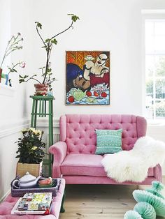 a living room filled with pink furniture and lots of pillows on top of it's back