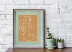 an art print on a shelf next to a potted plant