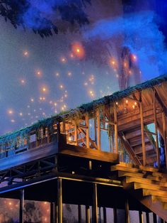 a train is going down the tracks on a bridge at night with bright lights above it