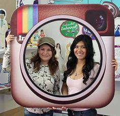 two women are holding up a polaroid camera