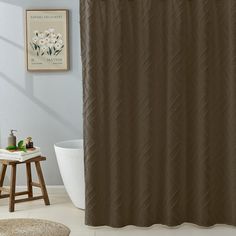 a bathroom with a brown shower curtain next to a white bath tub and wooden stool