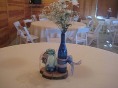 a blue vase filled with flowers sitting on top of a wooden slice next to a jar