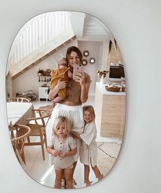 a woman taking a selfie with her two children in front of a mirror on the wall