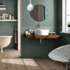 a bathroom with green walls and white fixtures, including a round mirror above the sink