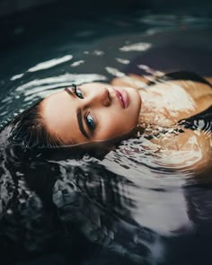 a woman is swimming in the water with her eyes closed and looking at the camera