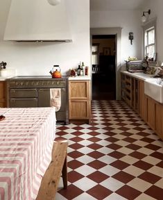 a kitchen with checkered flooring and an oven in the center, counter tops on both sides