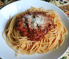 a white plate topped with pasta covered in marinara sauce and parmesan cheese