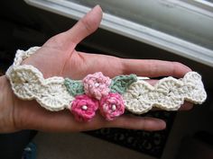 a hand is holding some crocheted flowers