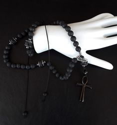 Inspired by the traditional Orthodox Rosaries also known as κομποσκοίνια. The Ankh Orthodox Rosary (v. 50) is an elite line rosary that follows the 50 knots pattern. Created in the holy Mt Athos, completed in the famous Mt Pelion and blessed directly by the Orthodox Church. Shaped solely with top notch materials that are based on Volcanic Lava Stones, 925 Pure Silver and completed with a Stainless Steel black Ankh Cross. . Moreover, the rosary has been officially blessed by the Orthodox church. Spiritual Obsidian Jewelry With Natural Stones, Spiritual Onyx Beads Jewelry 8mm, Black Spiritual Beaded Jewelry, Spiritual Obsidian Jewelry For Meditation, Adjustable Spiritual Obsidian Jewelry, Silver Healing Jewelry With 108 Beads, Spiritual Obsidian Round Bead Jewelry, Spiritual Obsidian Jewelry With Round Beads, Silver Healing Beaded Jewelry