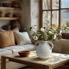 a white vase filled with flowers sitting on top of a table next to a couch