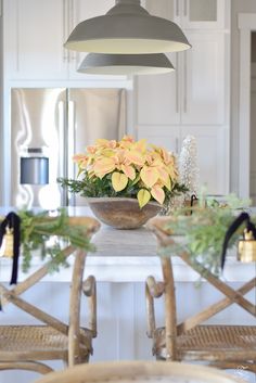 a table with some chairs and flowers on it in a room that has white walls