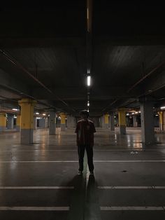 a man is standing in an empty parking garage at night with his back to the camera