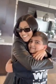 a woman hugging a young boy in a kitchen