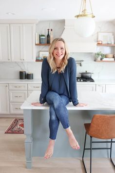 a woman sitting at a kitchen table with her feet up on the counter and smiling