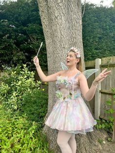 a woman in a fairy costume standing next to a tree