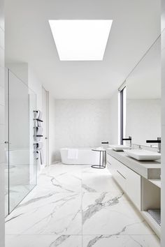 a white bathroom with two sinks and a bathtub in the middle of the room