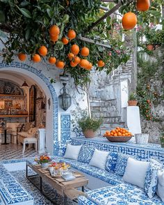 an outdoor living room with blue and white tiles on the walls, oranges hanging from the tree