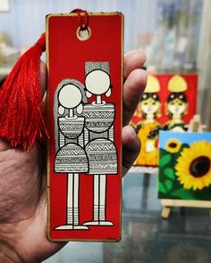 a person holding up a red bookmark with a drawing on it