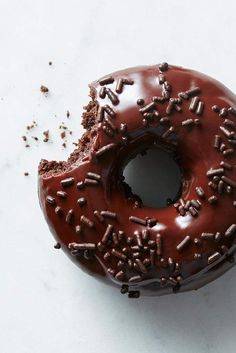 a chocolate donut covered in sprinkles on top of a white counter