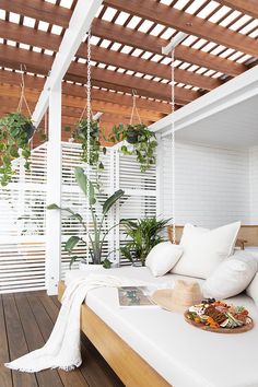 a bed with white sheets and pillows on top of it next to a potted plant