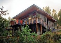 a large house sitting on top of a lush green hillside next to a wooded area