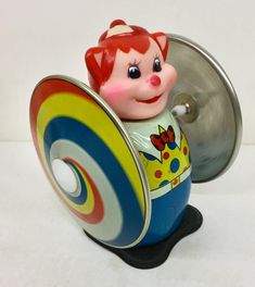 a small toy with a red hair and blue shirt on it's head sitting in a metal container