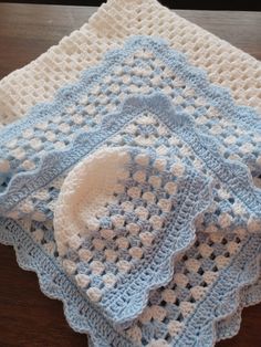 three crocheted afghans sitting on top of a wooden table