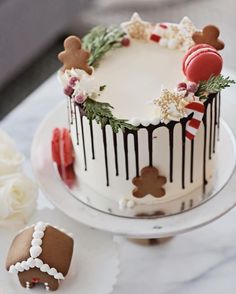 a decorated christmas cake sitting on top of a white table next to cookies and flowers