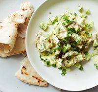 a white plate topped with food next to pita bread and green vegetables on top of it