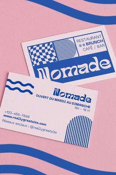 two business cards sitting next to each other on top of a pink surface with blue and white stripes