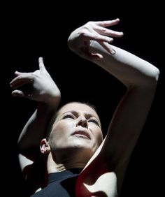 a woman with her arms stretched up in the air while wearing a black and red dress