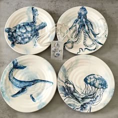 four blue and white plates with marine animals on them, one is holding an octopus