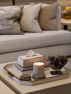 a tray that has some books and a candle on it in front of a couch