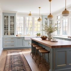 a large kitchen with blue cabinets and wooden counter tops, along with an area rug on the floor