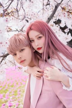 two young women standing next to each other in front of a tree with pink flowers