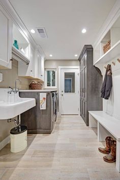 a long narrow kitchen with white cabinets and wood flooring, along with an open door leading to the laundry room