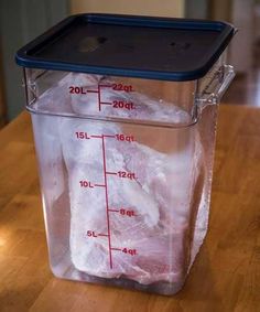 a plastic container filled with ice on top of a wooden table