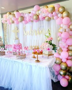 a table topped with lots of pink and gold balloons